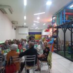 Pessoas sentadas a mesa,conversando, comendo e se divertindo em buffet infantil Zona Norte SP