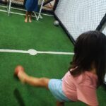 Menina chutando bola ao gol em mini campo em buffet infantil Zona Norte SP